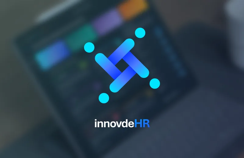 innovdeHR-Logo vor einem unscharfen Tablet mit dem innovdeHR-Dashboard